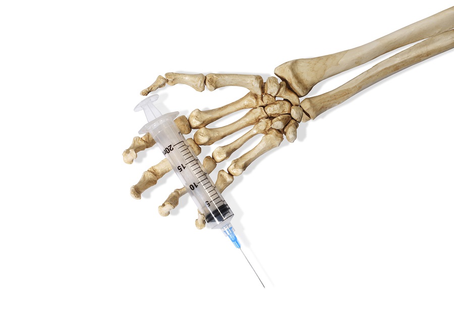 Still Life of a Skeleton Hand Holding a Medical Hypodermic Needle on a White Background